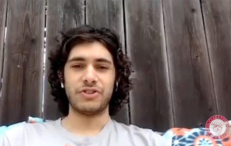 Ryan Nazari sitting in front of a wooden fence