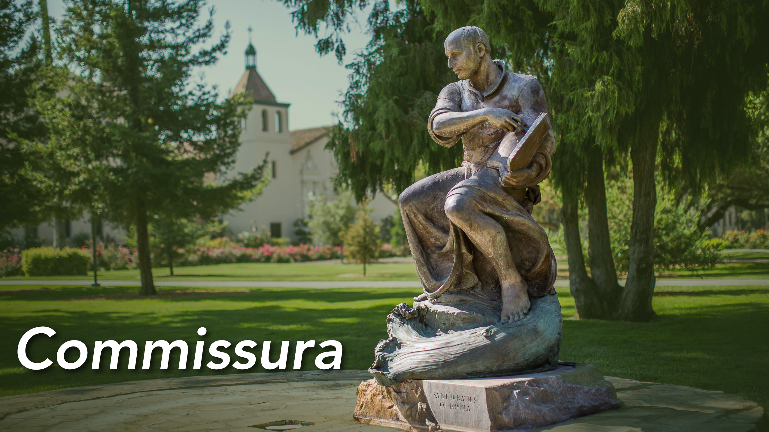 A statue of St. Ignatius of Loyola in contemplation with Santa Clara University in the background. Text in the bottom left reads Commissura