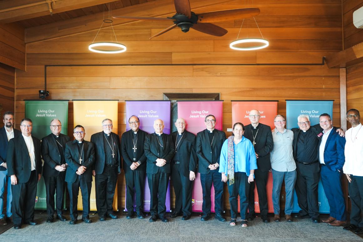 A group of people smiling in front of a wooden wall and colorful banners