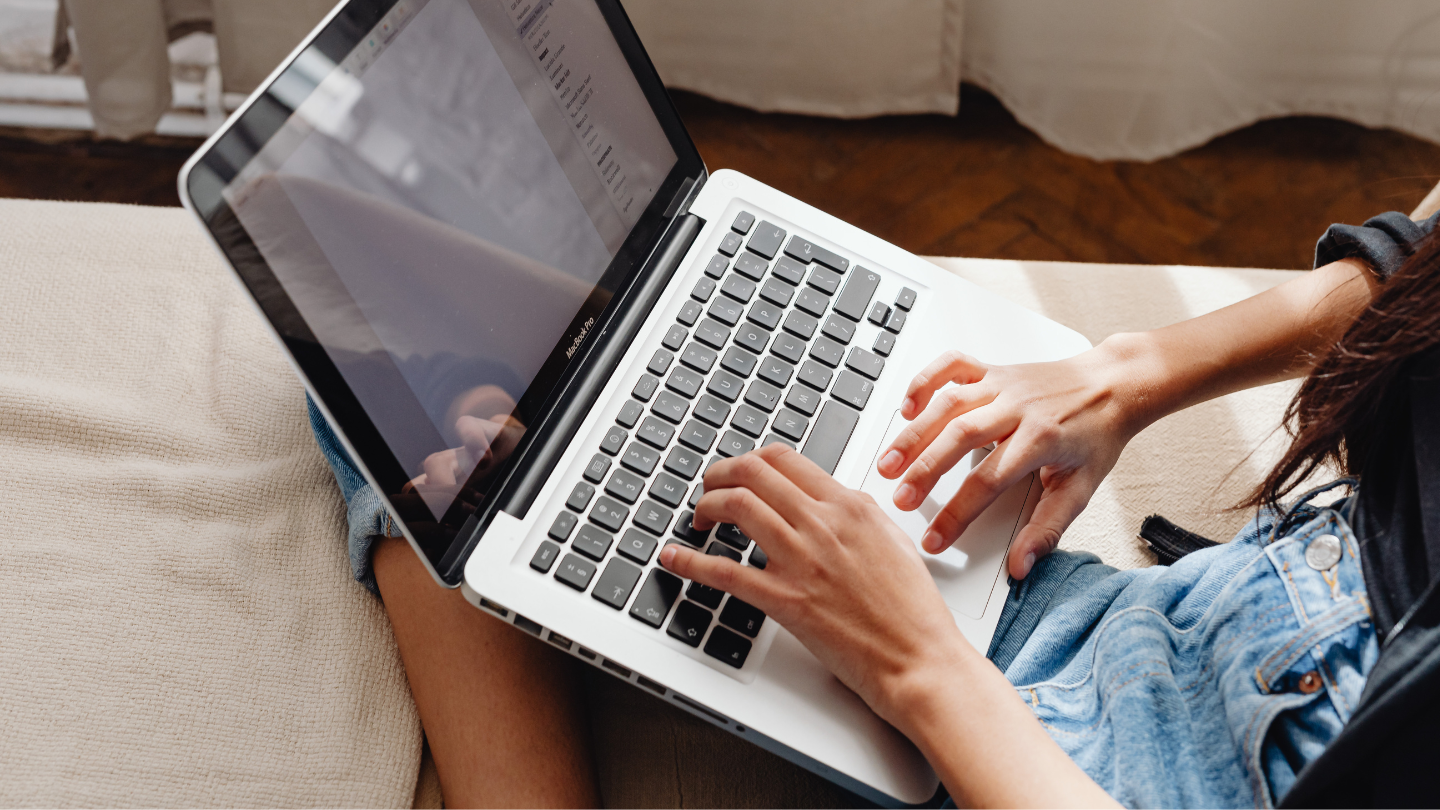 An individuals hands typing on a computer. 