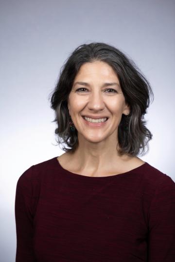 A woman smiling in a headshot with a gray background.