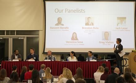 Panel discussion with presentation screen showing Actg Panel 2018 and audience watching.
