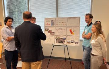 Students standing next to presentation board