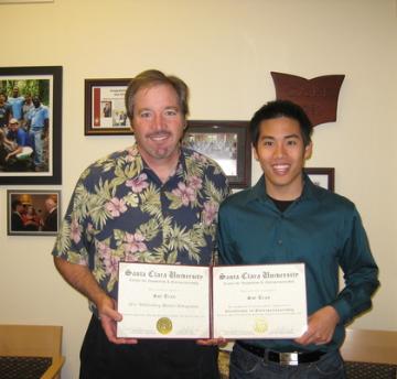 Two people holding a certificate titled 2011 Outstanding Student Entrepreneur in a room.