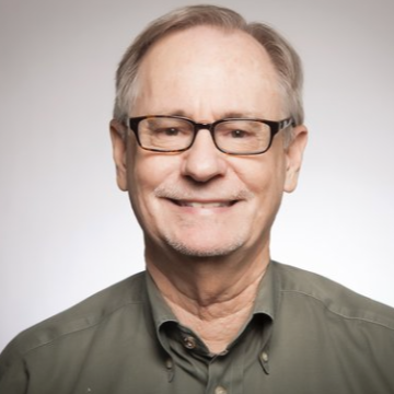 A person wearing glasses and a green shirt, smiling.
