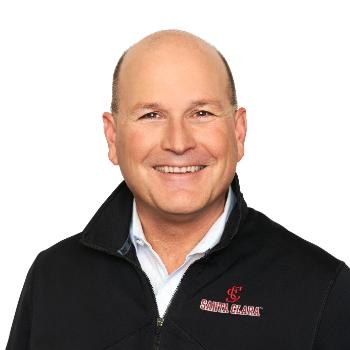 A man smiling, wearing a black zip-up jacket with LogMeIn logo.