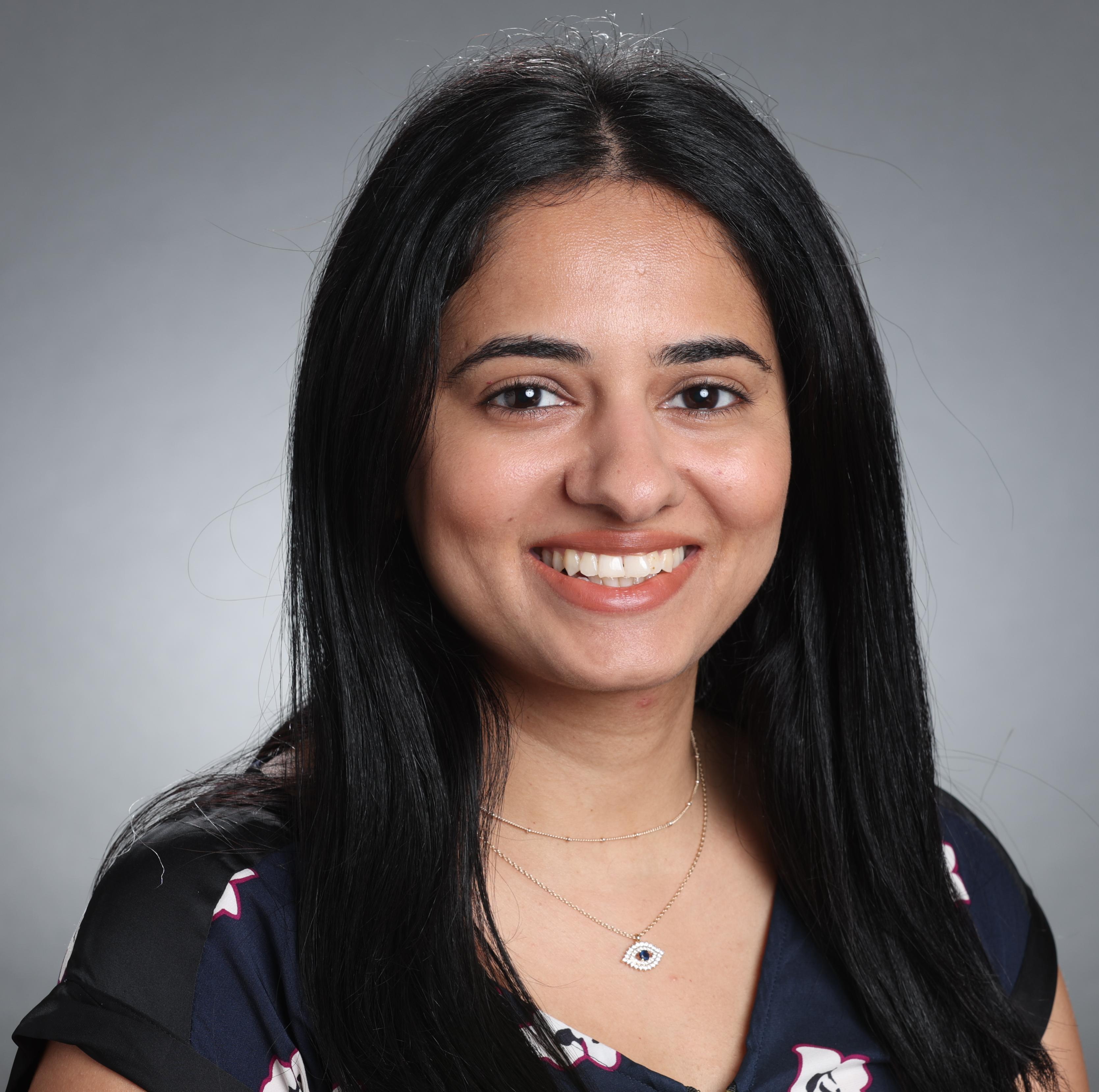 A person smiling against a gray background.