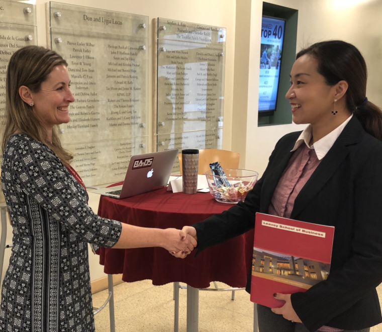 A student in a career fair shaking hands with an employer