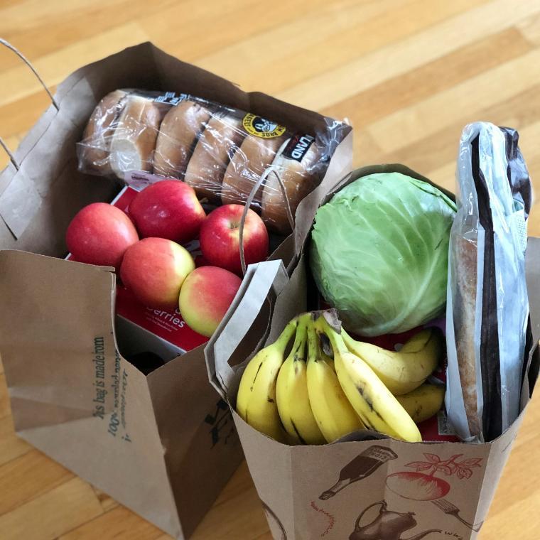 Paper bags with groceries including fruits and vegetables and bread 