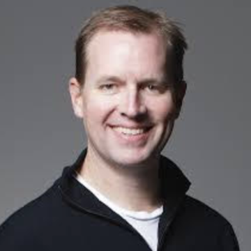 A person smiling against a gray background.