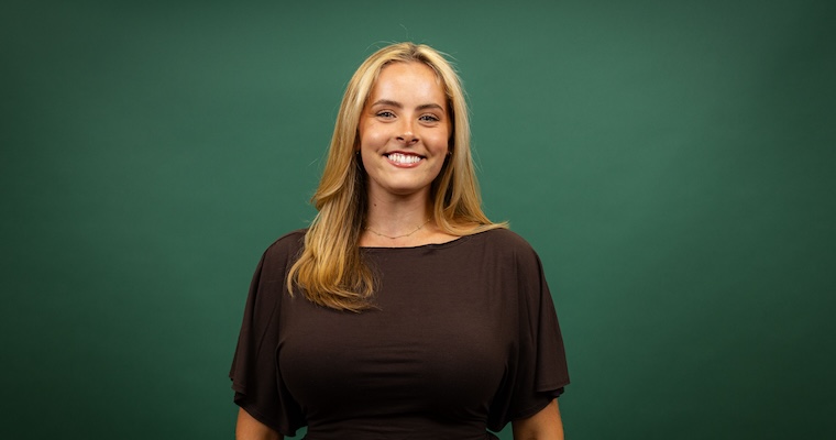 Young woman smiles in front of green backdrop. image link to article