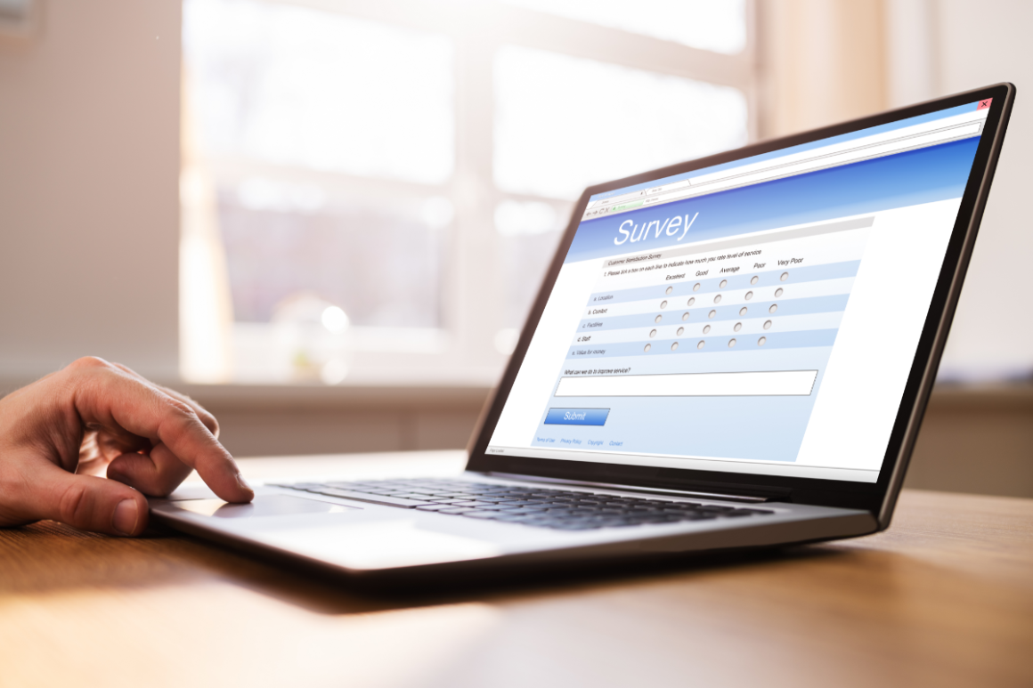 Hand using a laptop displaying an online customer satisfaction survey.