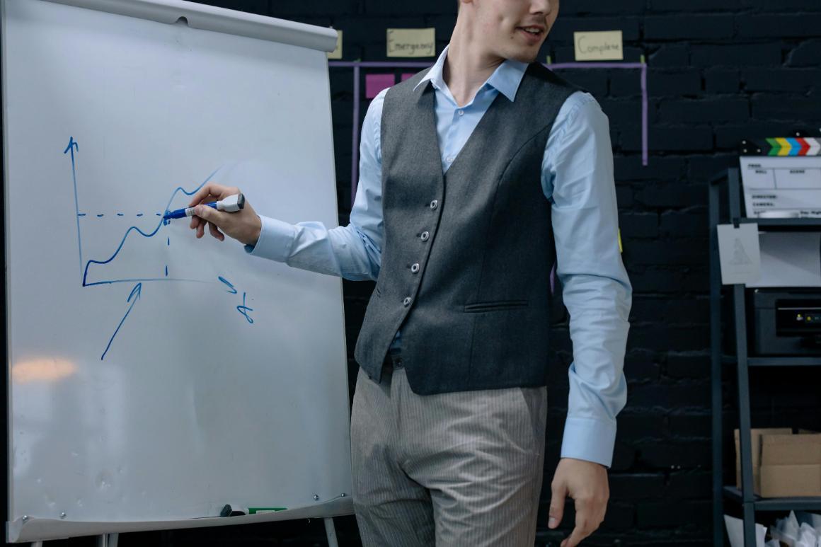 Business professional in a suit vest drawing graph on whiteboard