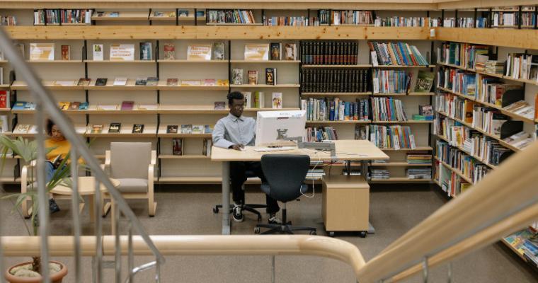 A serene library setting with a man studying and bookshelves filled with diverse literature