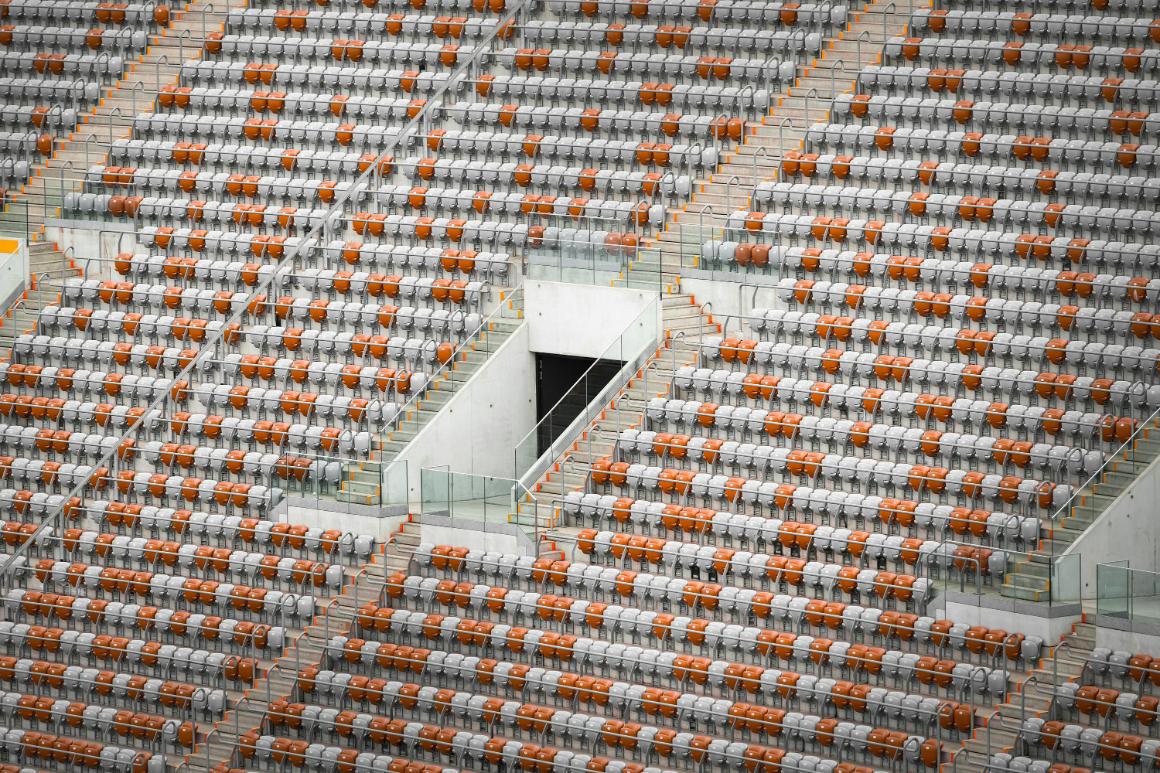 Empty stadium seats arrayed in a geometric pattern with alternating orange and gray colors