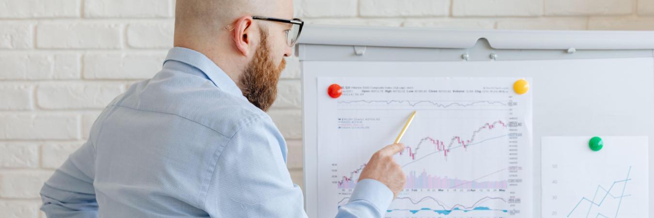 Man pointing to financial charts on a presentation board.