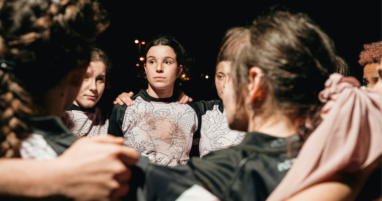 Womens athletes team huddle during a night game