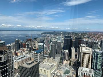 Aerial view of Seattles downtown buildings and waterfront under a blue sky.