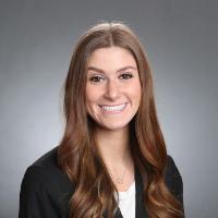 A person smiling against a plain gray background.
