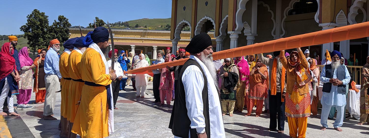 People gathered outside a Sikh gurdwara with colorful attire.