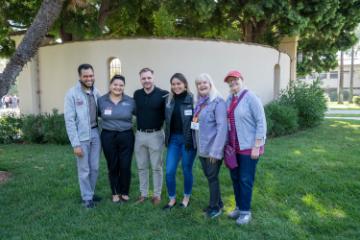 A group of 6 alumni smile at the camera