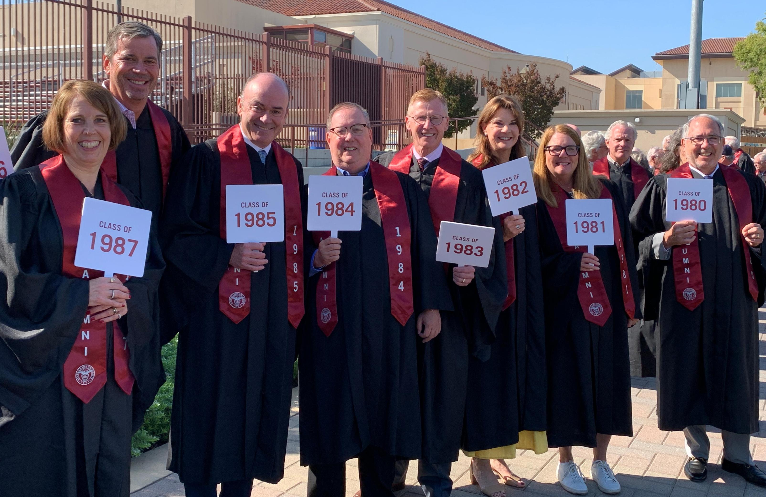 A group of people wearing robes holding signs with names.