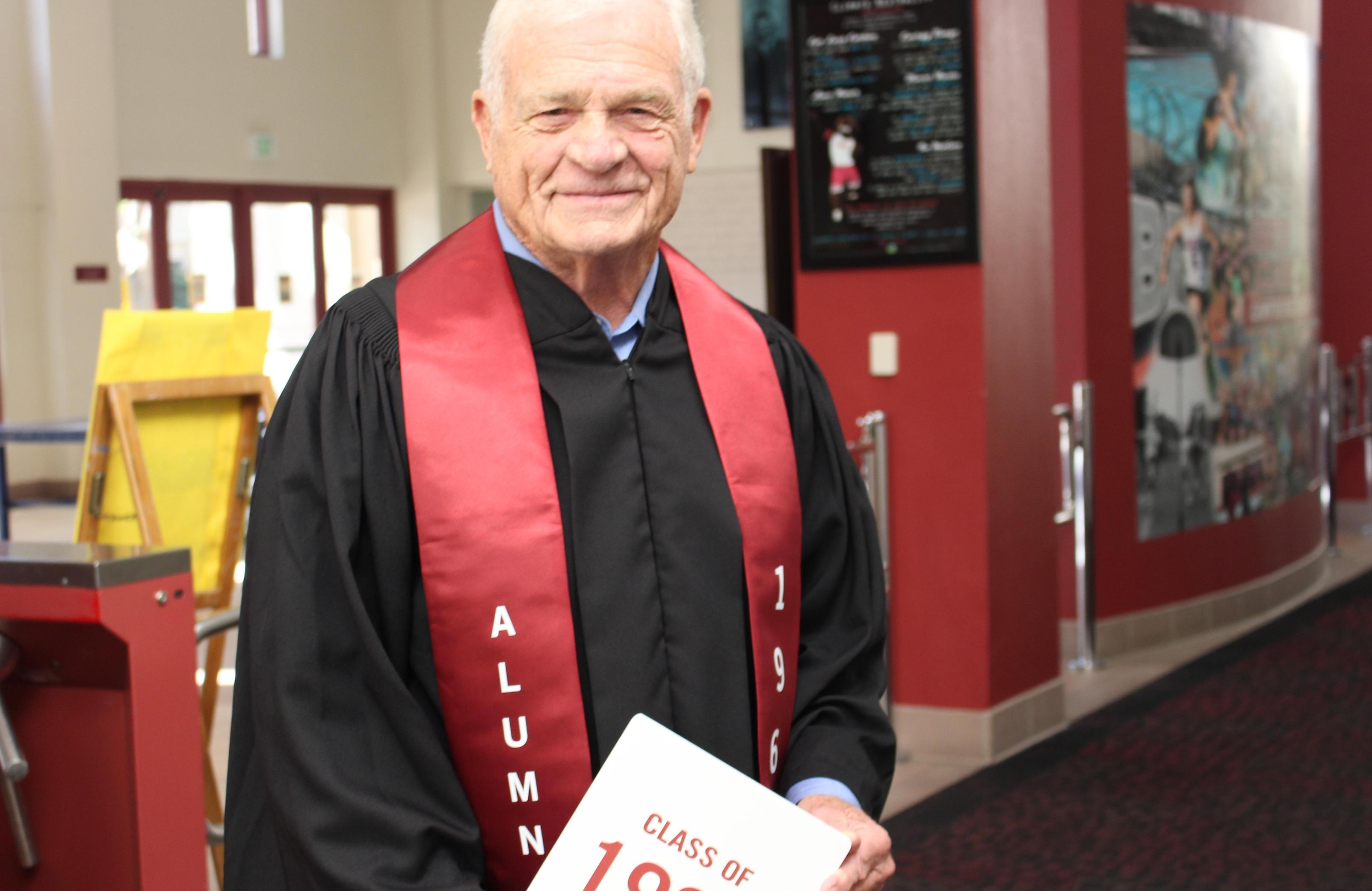 A person in black and red ceremonial attire, holding a document.