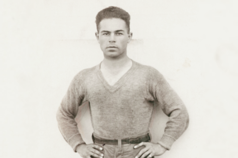 A young man with his hands on his hips and a solemn expression 