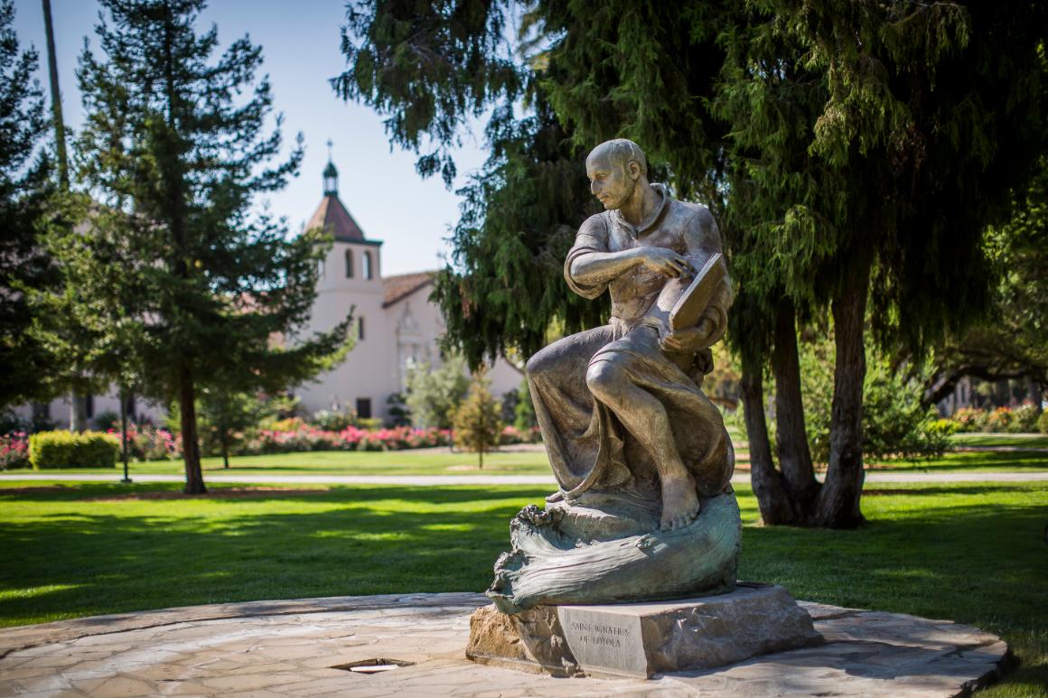 Statue of Saint Ignatius of Loyola, with Mission Santa Clara de Asís in the background.