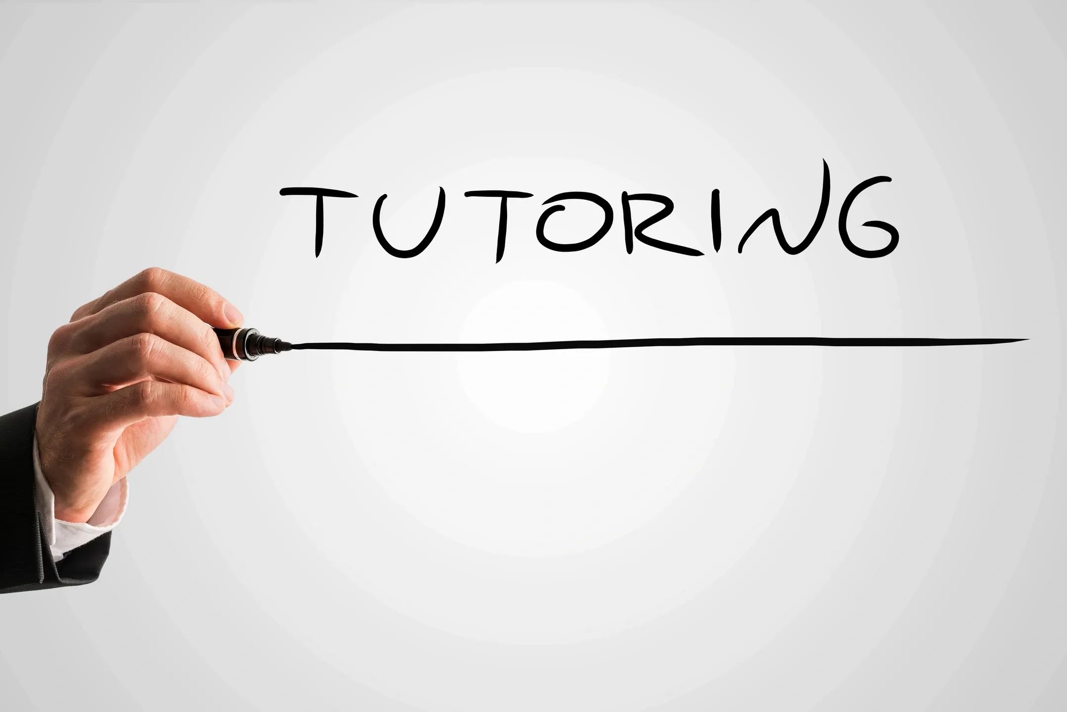 Hand dragging an expo marker across glass with a line under the word Tutoring