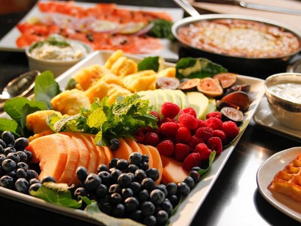 A platter of assorted fruits including blueberries, strawberries, raspberries, pineapple, and greens.