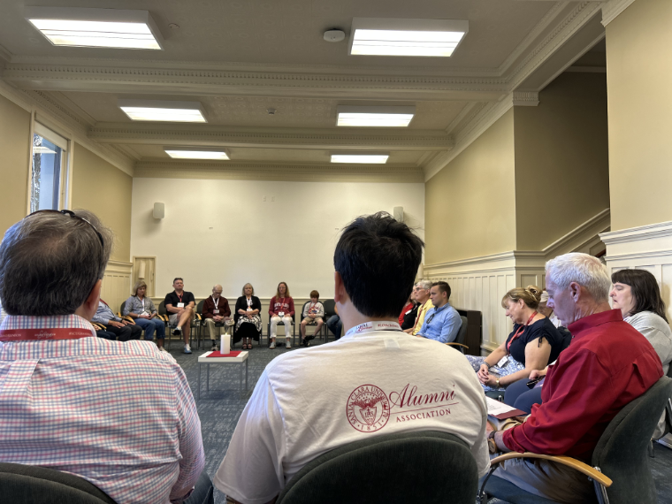 A group of alumni sitting in a circle with their eyes closed