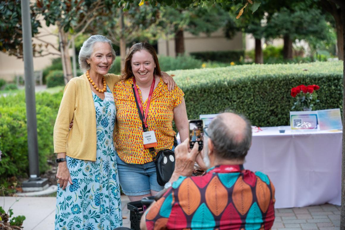 Two women posing as a man takes their picture on a cell phone at Santa Clara Universitys LGBTQ+ Alumni Social at Grand Reunion.