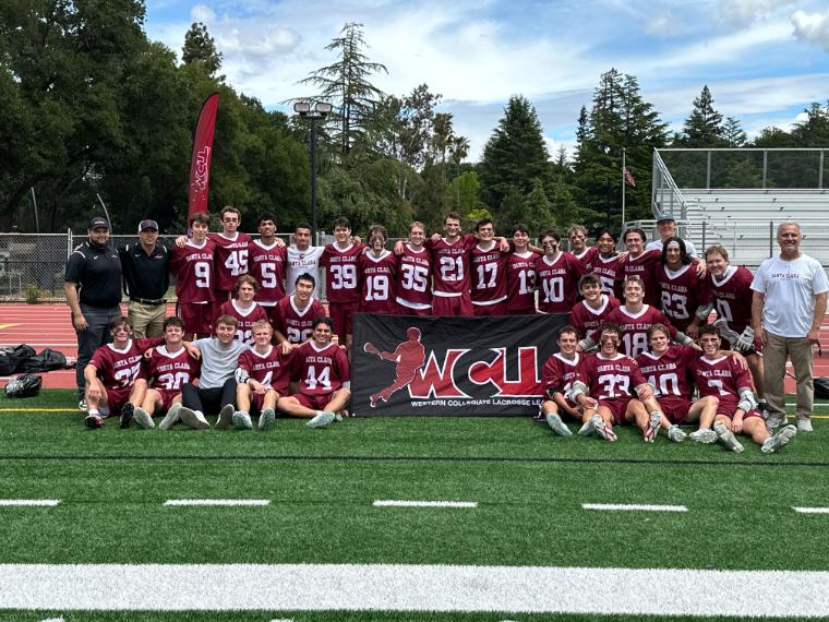 Large group photo of Mens Lacrosse players in uniform standing and sitting in two rows with a tournament banner