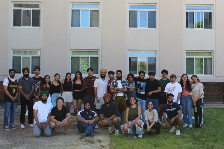 A group of Sikh students gathered in front of a campus building for a photo