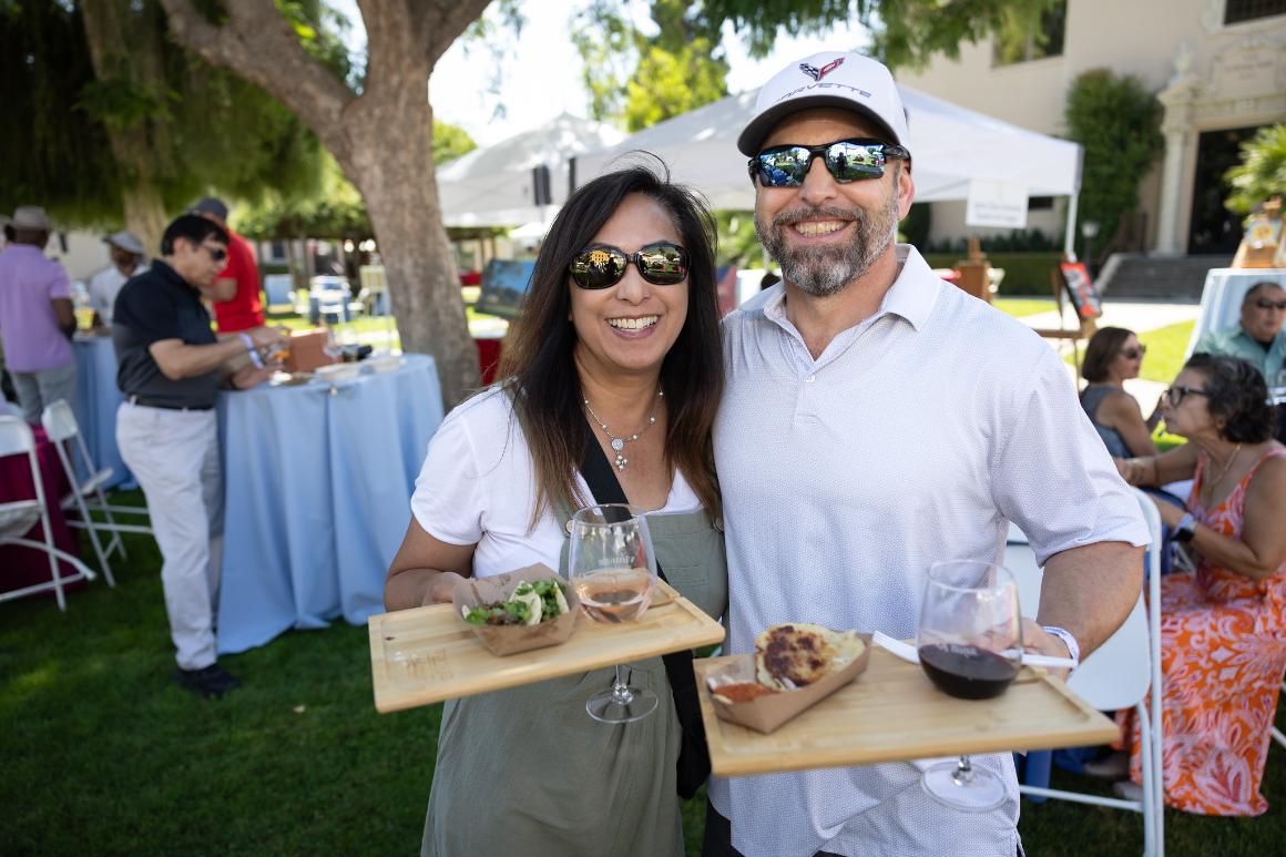 Two people holding wine trays and smiling at the camera
