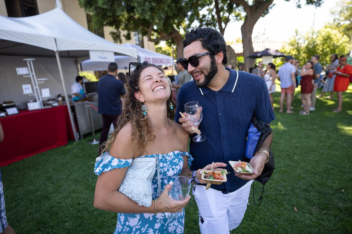 A couple laughs while they walk toward the camera in the Mission Gardens