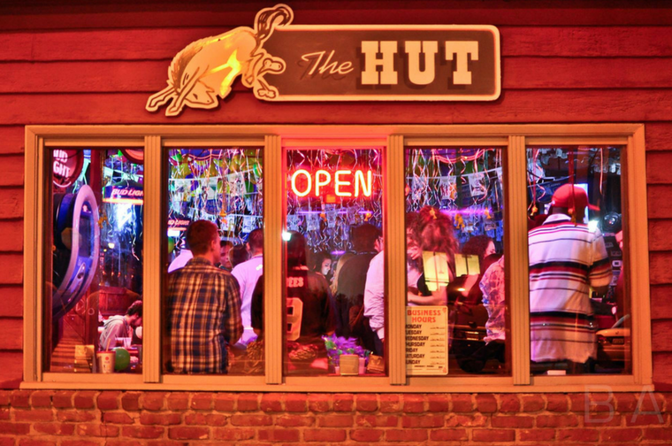 People inside a restaurant with an OPEN neon sign and a The Hut sign above.