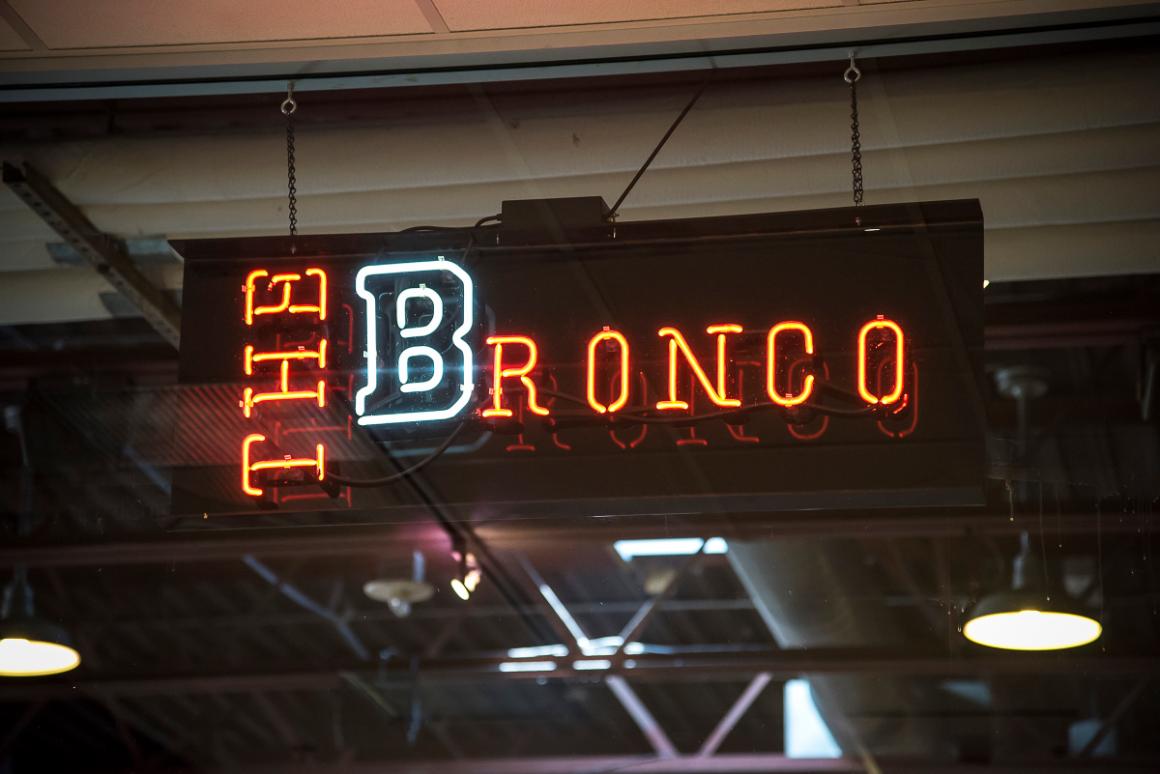 Neon sign that reads The Bronco inside a building.