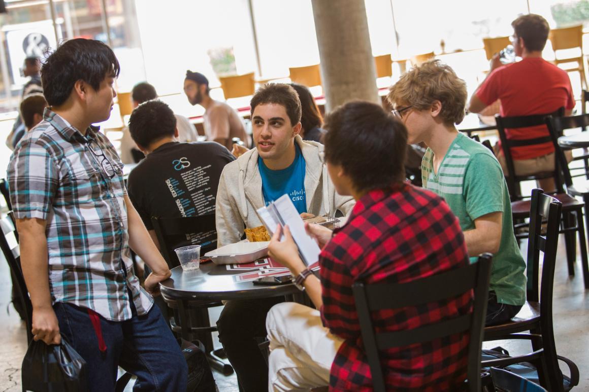 A group of four people conversing around a small table.