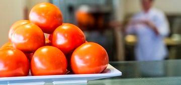 A stack of oranges with a person in a dining area background.
