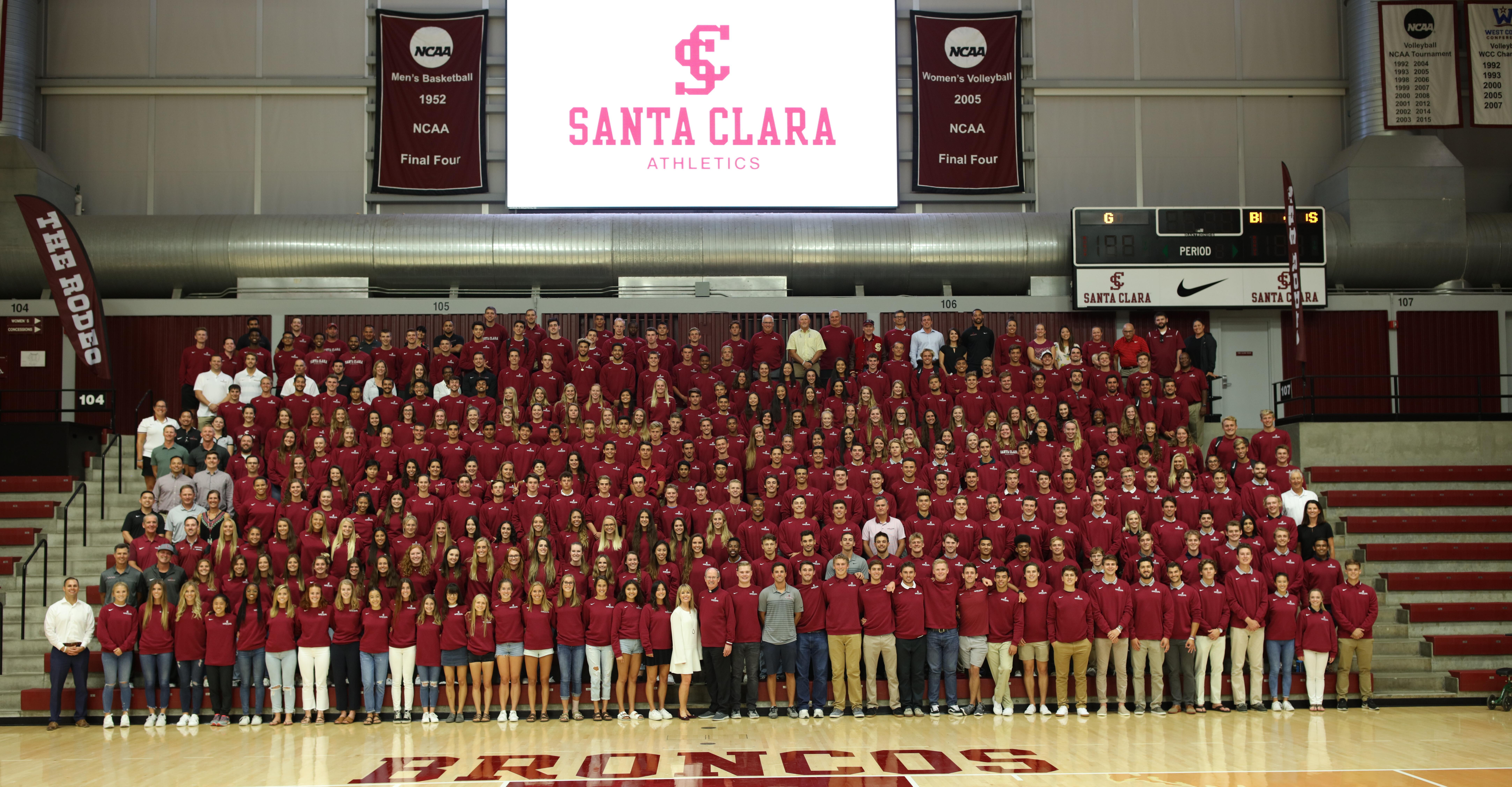 A group photo of student athletes in a gymnasium with Welcome Back displayed on the screen.
