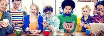 Group of people looking at electronic devices; titled Hero Feature Banner.