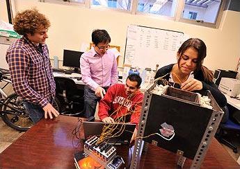 Four people collaborating around a computer in an office setting.
