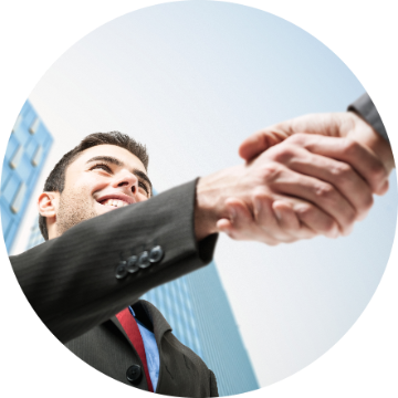 Two people shaking hands outdoors, smiling and formal attire.