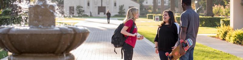 Students standing near fountain with Mission Church in the background 