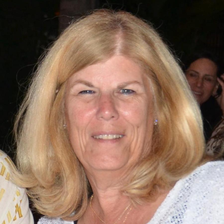 A person with a light-colored top, smiling at the camera.