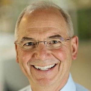 A smiling man wearing glasses and a tie.