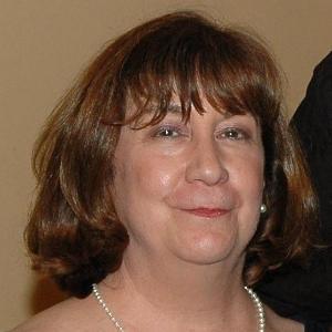A woman smiling with a neutral background.
