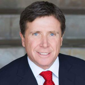 A person in a suit and red tie smiling.